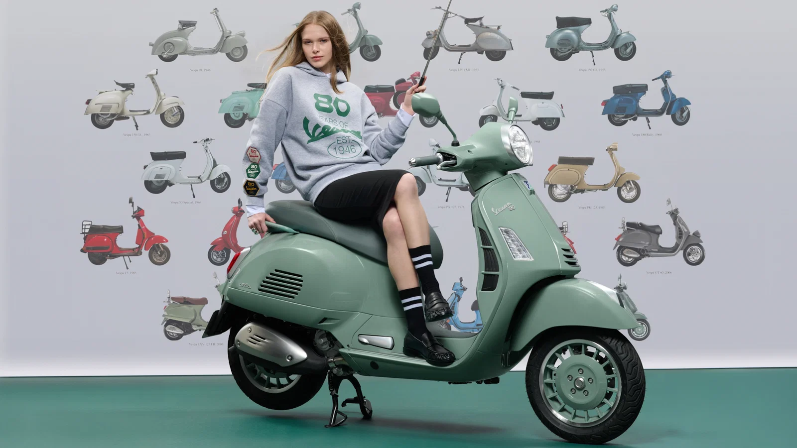 Vespa-Roller vor einer Wand mit Vespa-Motiven.