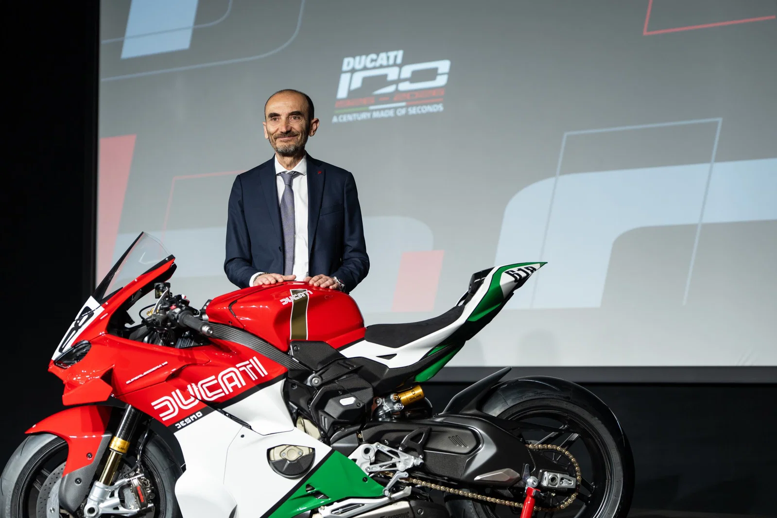Claudio Domenicali steht mit einem Ducati-Motorrad.